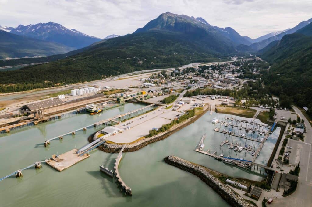 A town with various docks and marinas sits at the edge of a mountain range.