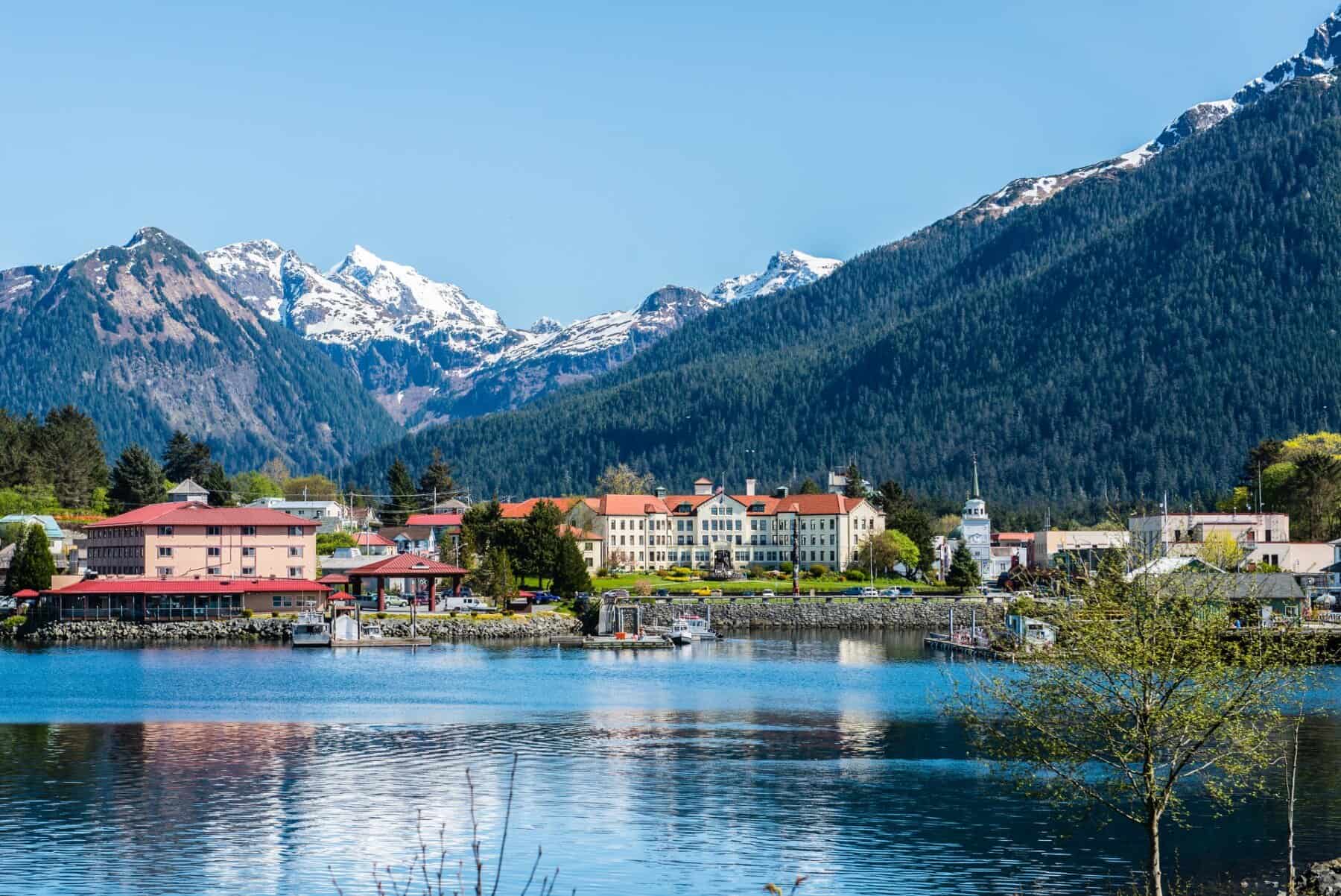A town sits on the shore of the ocean surrounded by mountains.